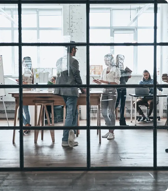 Group of modern professionals working together behind a glass wall in a boardroom