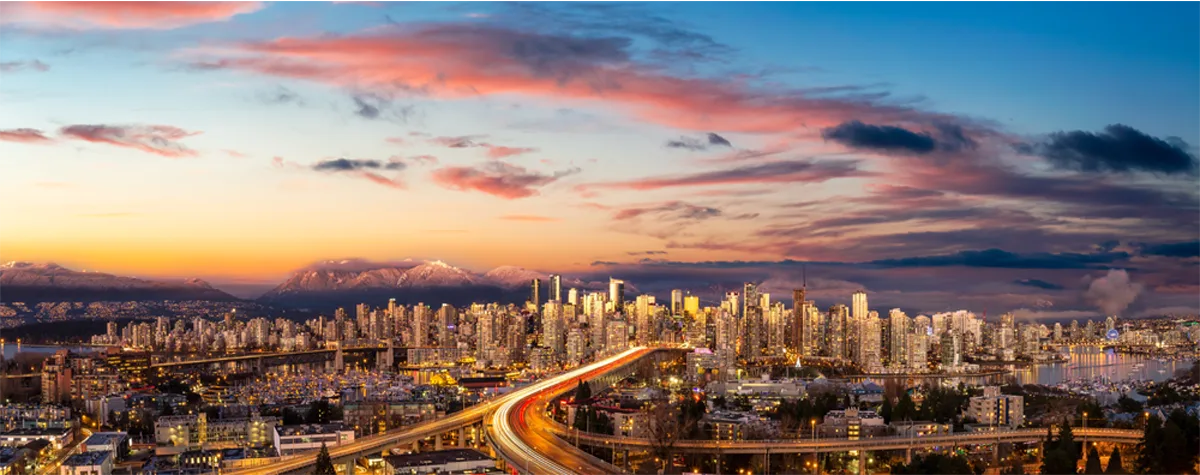 Aerial panoramic view of Downtown Vancouver, Cambie Bridge, and False Creek at a cloudy sunset.